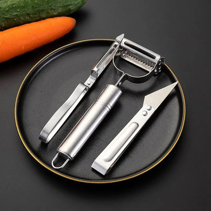 Clarify.pk 3 in 1 kitchen peeler and grater set in stainless steel on black plate with carrot and cucumber