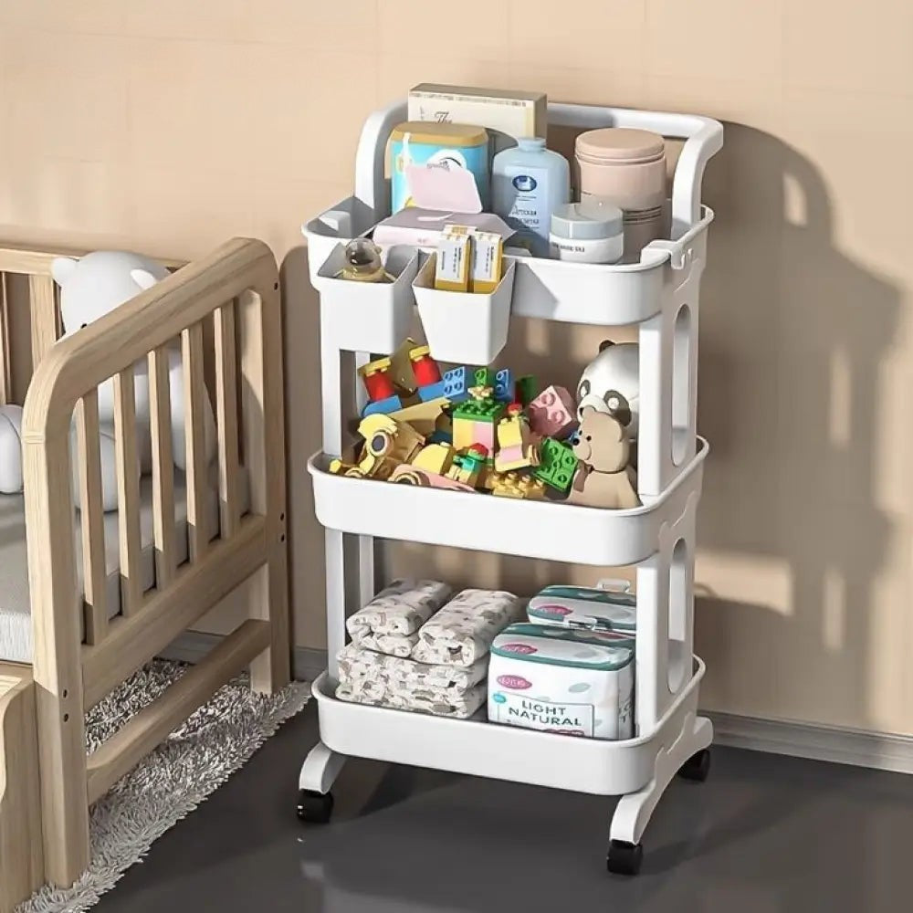 3 tier folding metal cart with wheels holding toys, baby supplies, and toiletries beside wooden crib