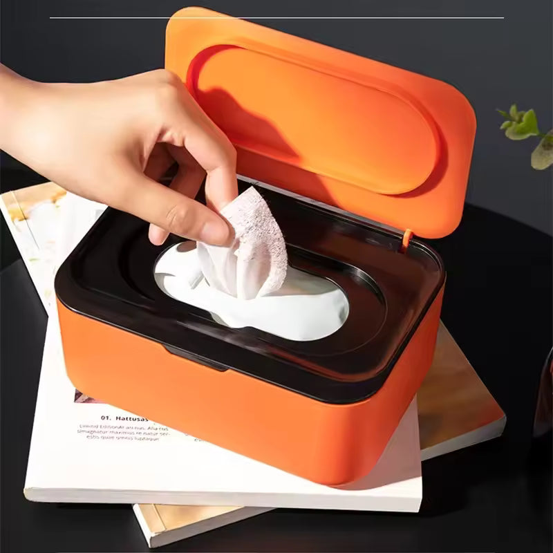Clarify.pk orange wet wipes dispenser with lid and black top being used to pull a wipe
