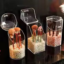 Set of clear acrylic cosmetic organizer storage boxes holding makeup brushes in decorative beads