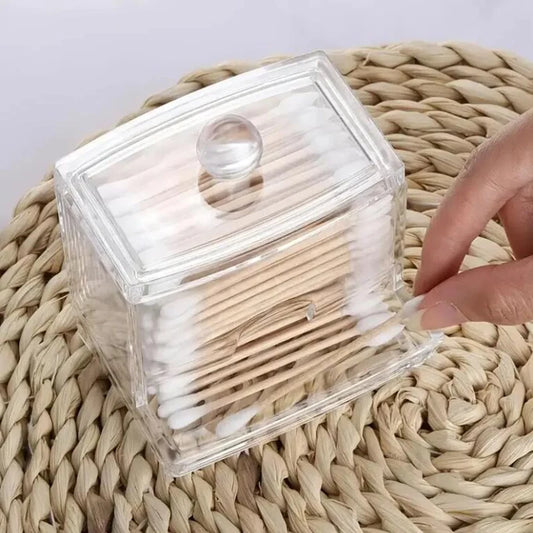 Clear acrylic cotton swab storage box with lid, holding wooden cotton swabs on a woven mat