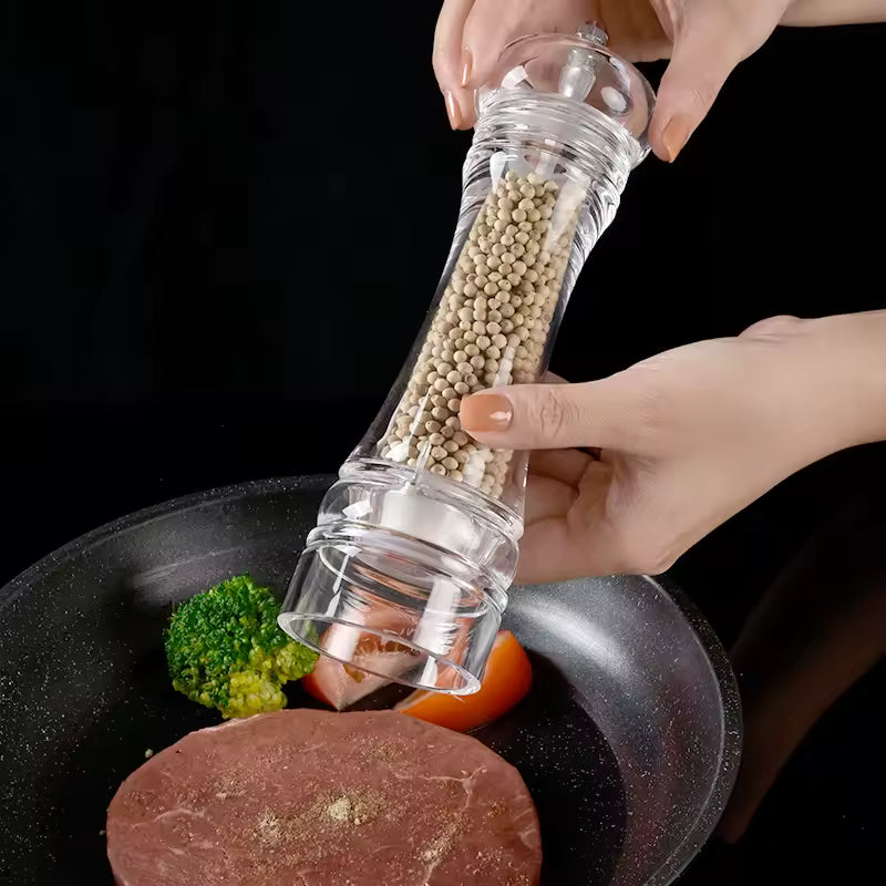 Acrylic manual paper grinder salt and pepper mill from Clarify.pk being used to season steak in a pan with vegetables