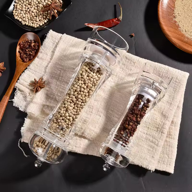 Acrylic manual paper grinder salt and pepper mills filled with white peppercorns and black peppercorns on cloth