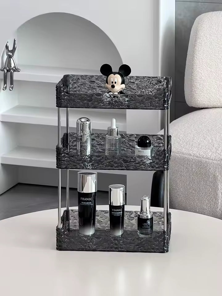 Clear acrylic shower organizer with three tiers holding various cosmetic bottles and a Mickey Mouse decoration