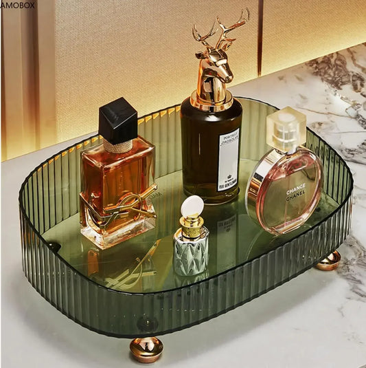 Elegant transparent dresser storage box with dark ribbed sides and gold feet holding perfume bottles