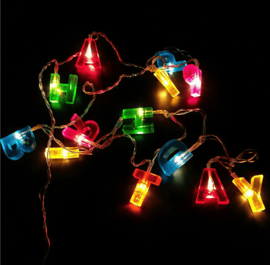 Colorful birthday decoration string lights with illuminated letters on a dark background