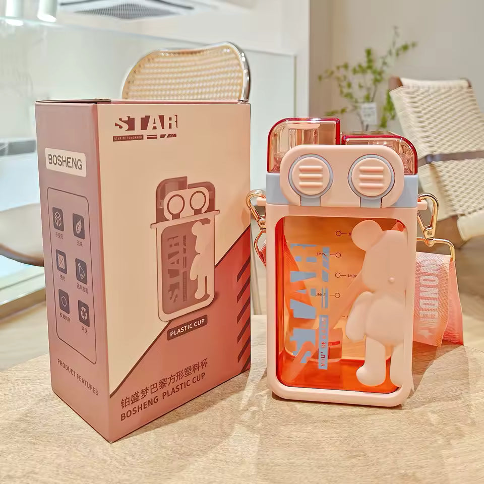 Cartoon bear water bottle in orange with bear design and carrying strap by Clarify.pk next to packaging box
