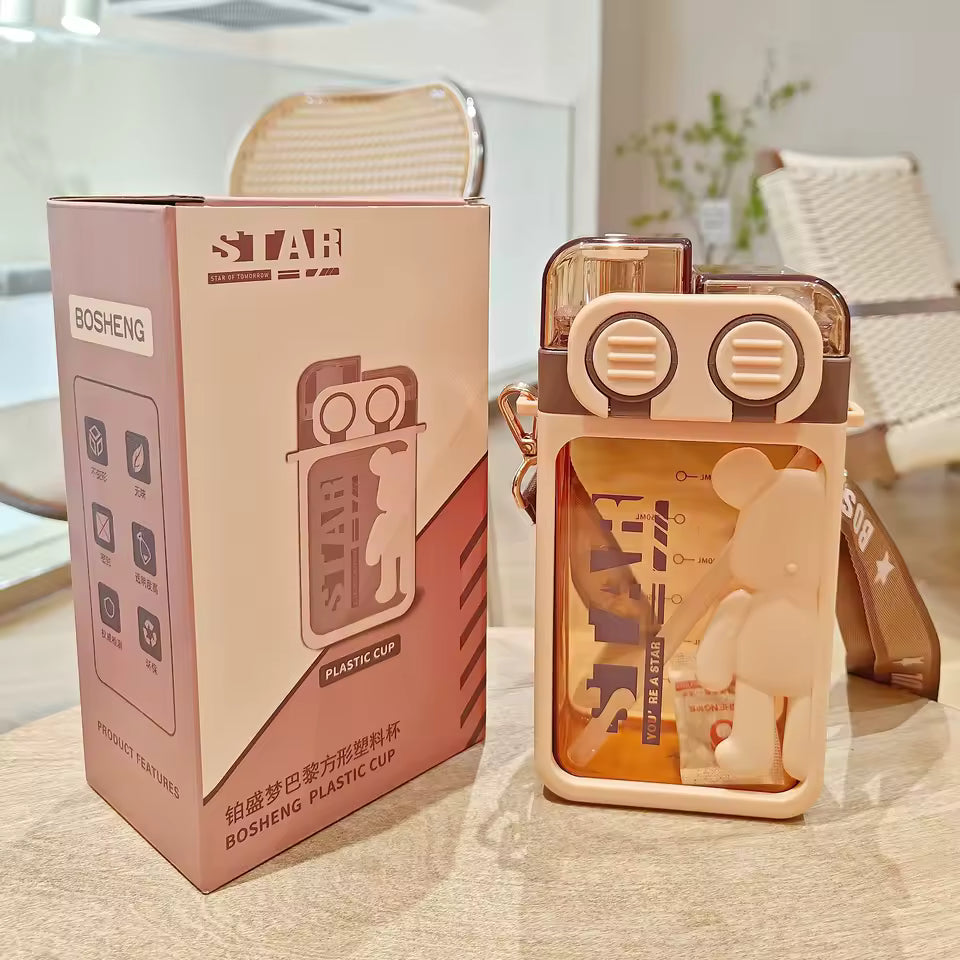 Cartoon bear water bottle in beige with bear figurine inside and matching box packaging on table