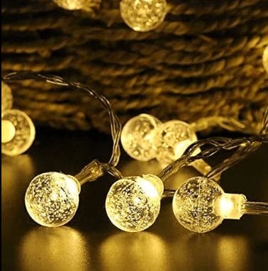 Warm white bubble ball LED string lights glowing with textured spherical bulbs on a clear wire