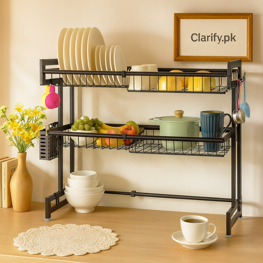 Expandable 2 tier over the sink rack in black metal holding plates, bowls, fruits, and kitchenware
