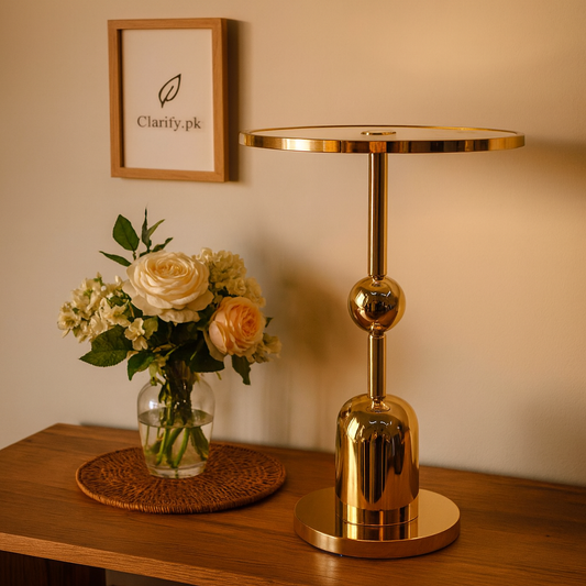 Luxury gold pedestal stand with polished finish displayed on wooden surface beside flower vase