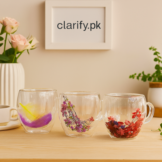 Set of three decorative double wall glass cups with colorful dried flowers and feathers inside on wooden table