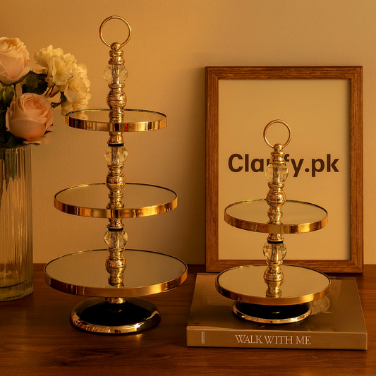 Elegant gold tiered dessert stand with three and two levels displayed on wooden surface with flowers and picture frame