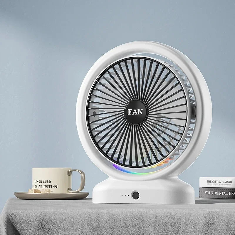 White colorful LED desk fan with circular grill and base placed on a gray surface next to a coffee cup and books