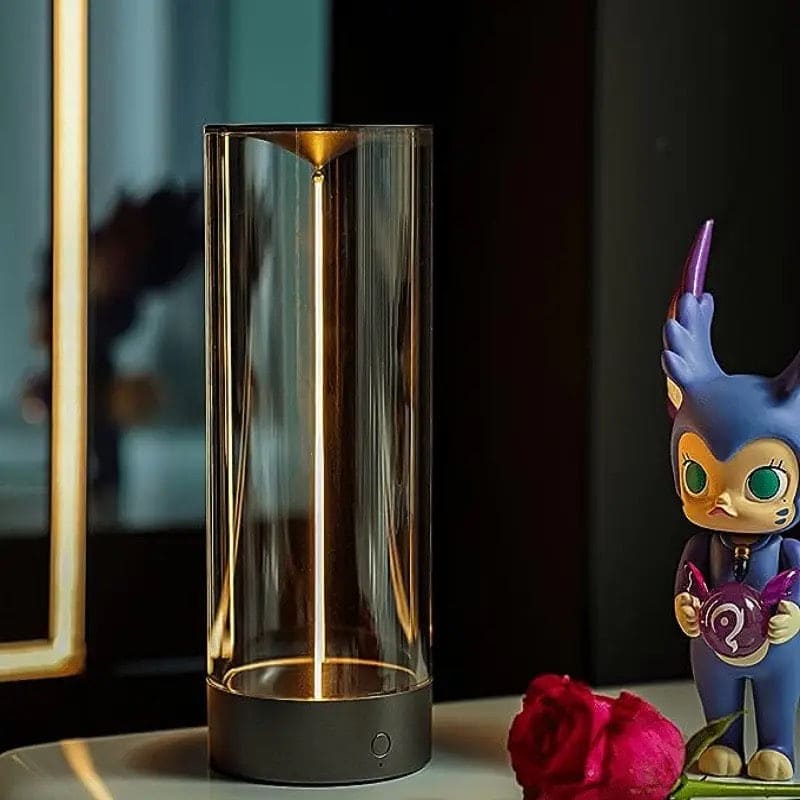 Clarify.pk cordless rechargeable table lamp with transparent cylindrical design on a table next to red rose and decorative figurine