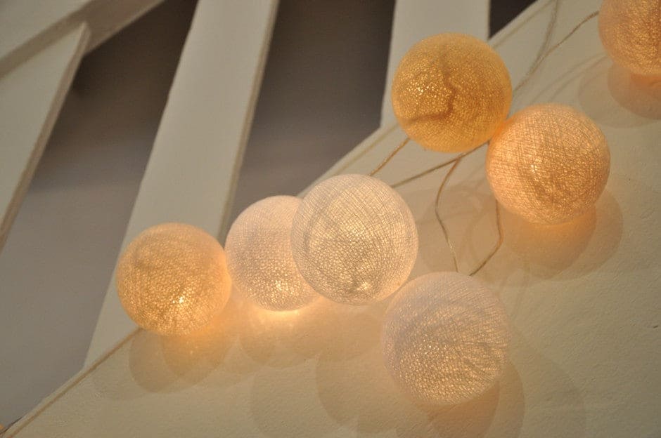 Warm glowing cotton ball string lights hanging indoors creating cozy ambient lighting