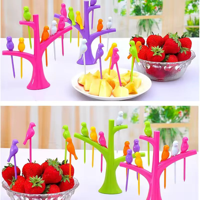 Colorful creative fruit forks set with bird-shaped handles displayed on pink, purple, and green tree stands holding strawberries and pineapple pieces