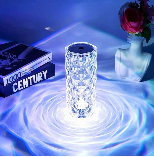Crystal lamp with bluetooth speaker emitting bright light on a table next to books and a decorative vase