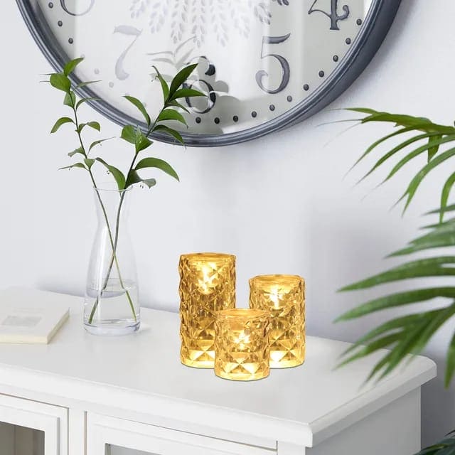 Crystal rose Crystal lamp set with warm golden light on white cabinet near green plants and wall clock