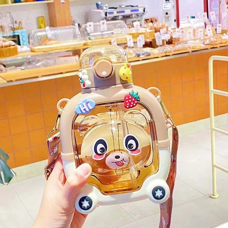 Cute bear water cup for kids with a bear face design and strap held in hand indoors