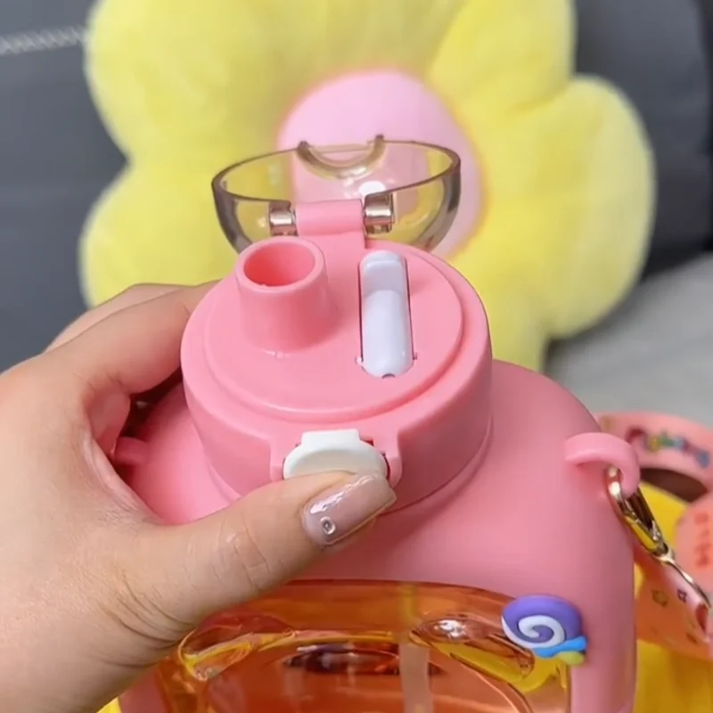 Hand holding a pink cute bear water cup for kids with flip-top lid and straw from Clarify.pk