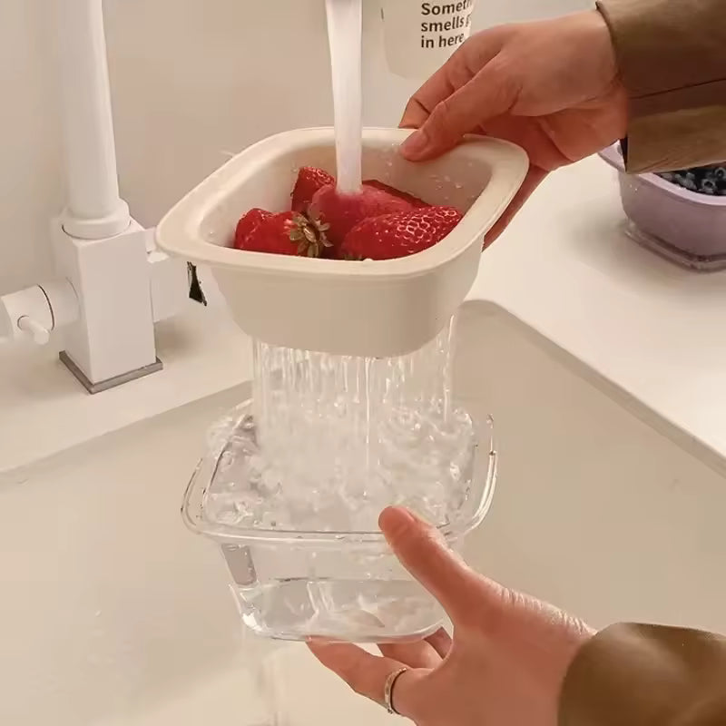 Hands holding a cute fruit drain basket washing strawberries with water draining into a clear container