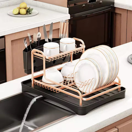Rose gold and black dish drying rack with cutlery holder placed on kitchen sink with white plates and cups