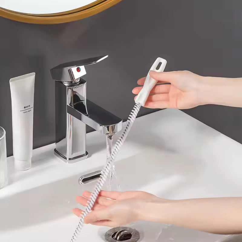 Hand using a drain clog remover tool to clear sink drain under running water in bathroom