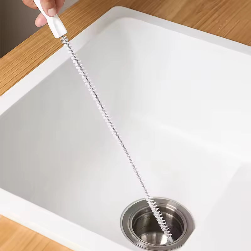Hand using a drain clog remover tool to clean a kitchen sink drain from Clarify.pk