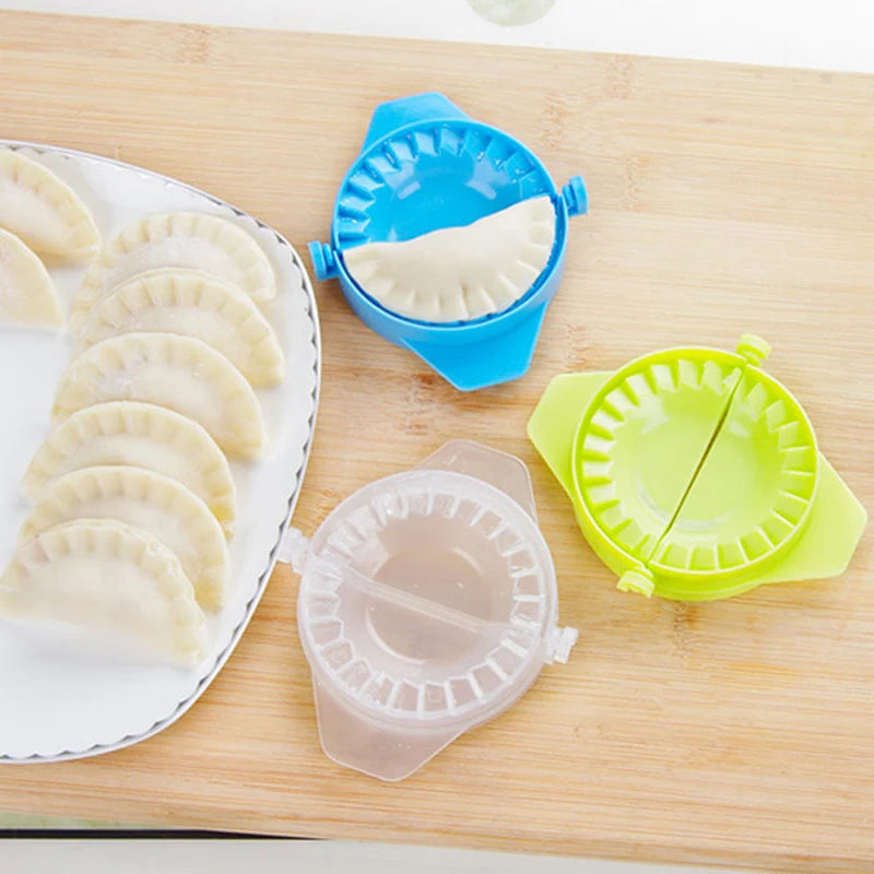 Colorful dumpling mold kitchen tool set with blue, green, and clear molds on wooden surface next to plate of uncooked dumplings