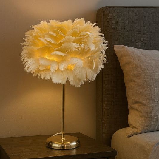 Warm glowing electric feather lamp with soft white feathers on a brass stand beside a bed