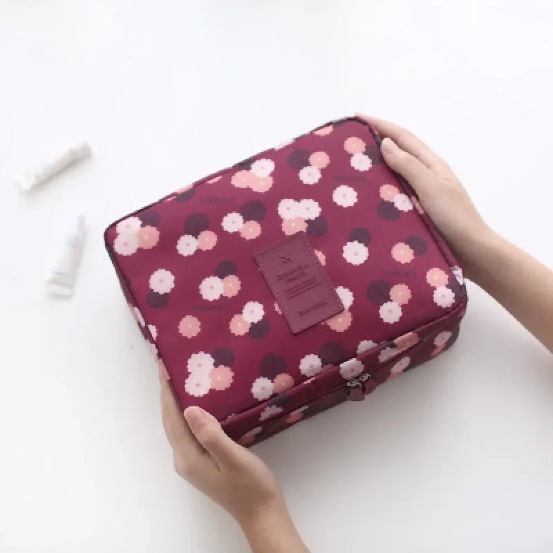 Hands holding pink floral makeup storage bag for women with zipper closure