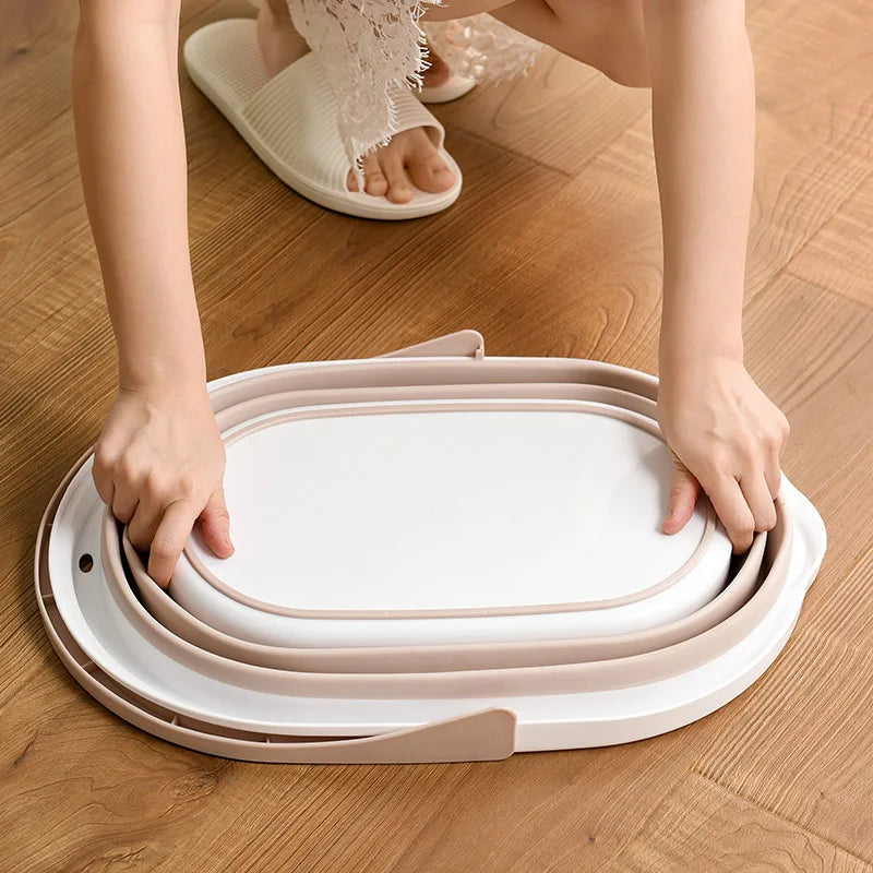 Person folding a beige and white folding mop bucket on a wooden floor for easy storage