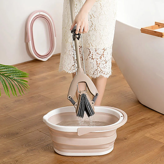 Person using a beige and white folding mop bucket on wooden floor near bathtub with mop wringer in hand
