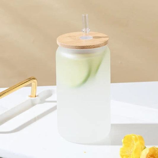 Frosted glass bamboo lid iced coffee mug with clear straw and lemon slices on white surface