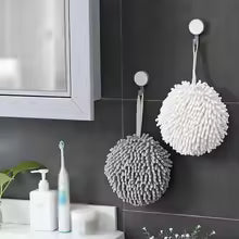 Gray and white fuzzy ball microfiber hand towel hanging in modern bathroom with tooth brush and sink