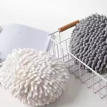 Gray and white fuzzy ball microfiber hand towel set placed beside a laptop and metal basket