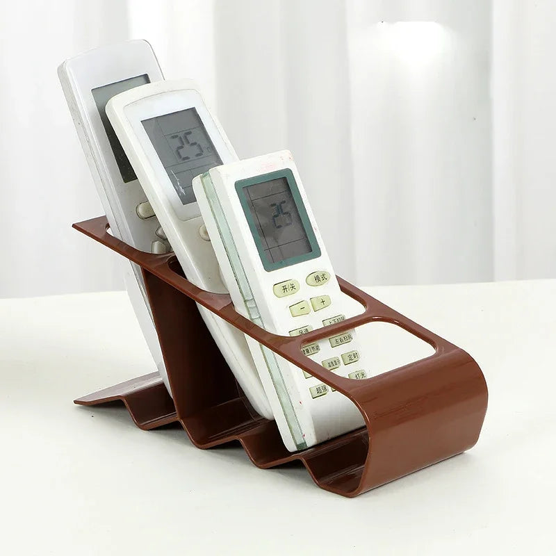 Brown plastic TV remote stand holder organizing three white remote controls on a white surface