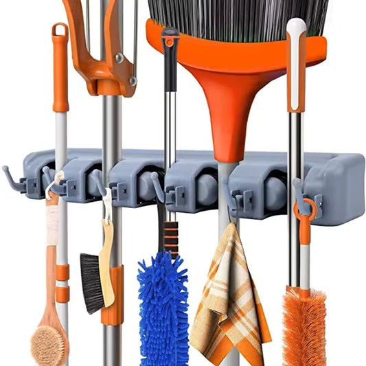 Wall mounted mop holder by Clarify.pk holding various cleaning tools with orange and gray accents