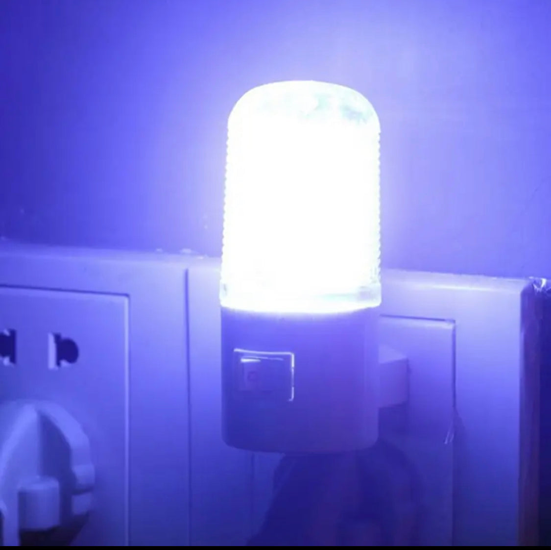 Bright white wall mounting night lamp plugged into electrical outlet emitting soft light