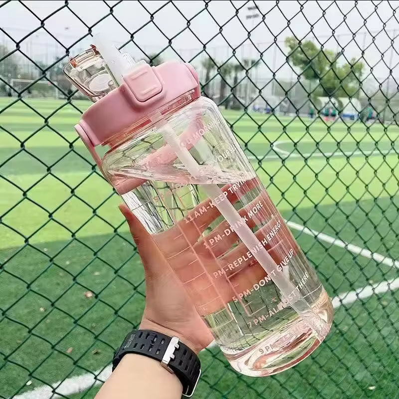 Clear 2 liter water bottle for girls with pink lid and motivational time markers held outdoors