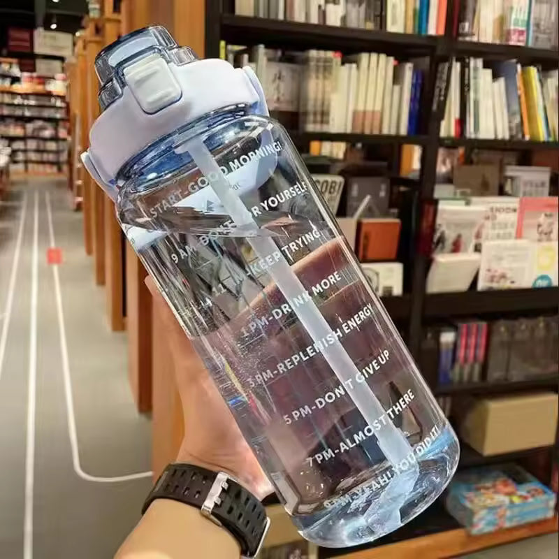 Clear 2 liter water bottle for girls with time marker and white flip cap held in hand