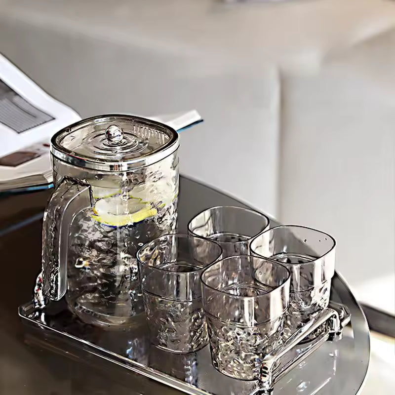 Glass juice pitcher with lid and four matching textured glasses on a silver tray by Clarify.pk