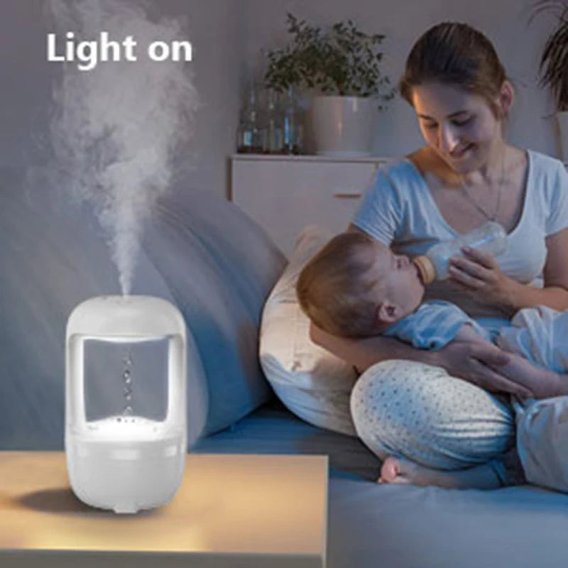 Glow in the dark air humidifier producing mist in a cozy room with mother feeding baby in background