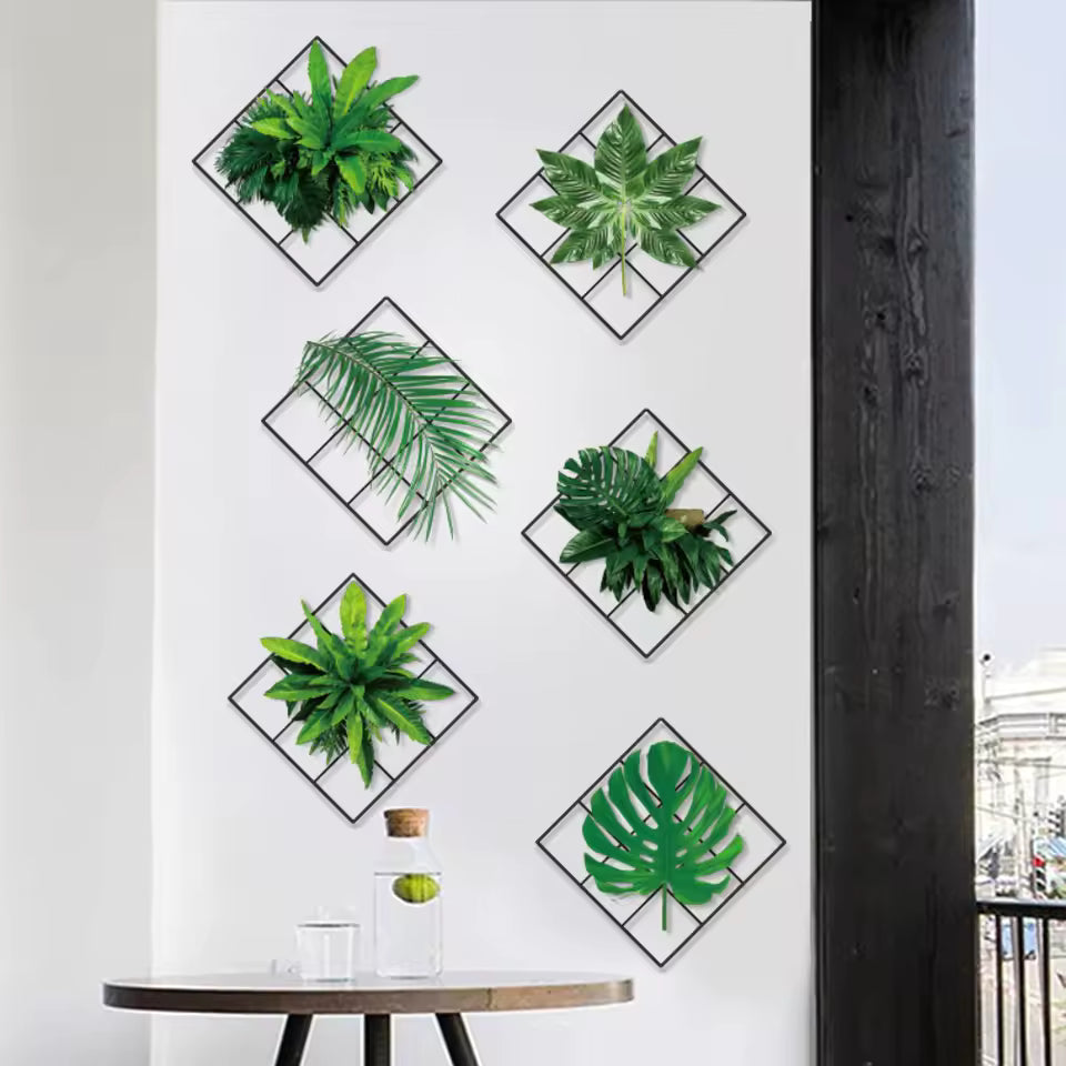 Decorative green plant wall stickers arranged in diamond frames on a white wall above a wooden table