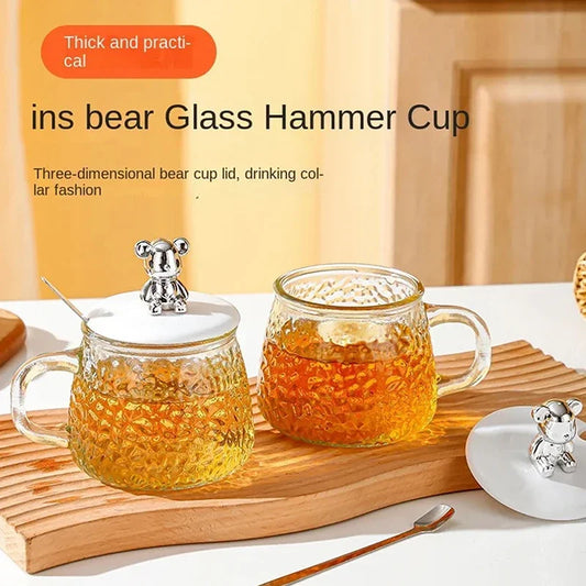 Clarify.pk hammered glass coffee cup with lid featuring a bear-shaped handle and textured design on wooden tray