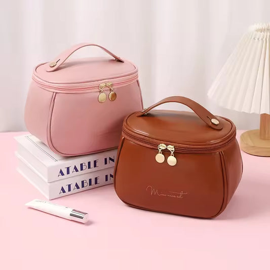 Two handheld makeup wash bags in pink and brown PU leather with gold zipper and handle