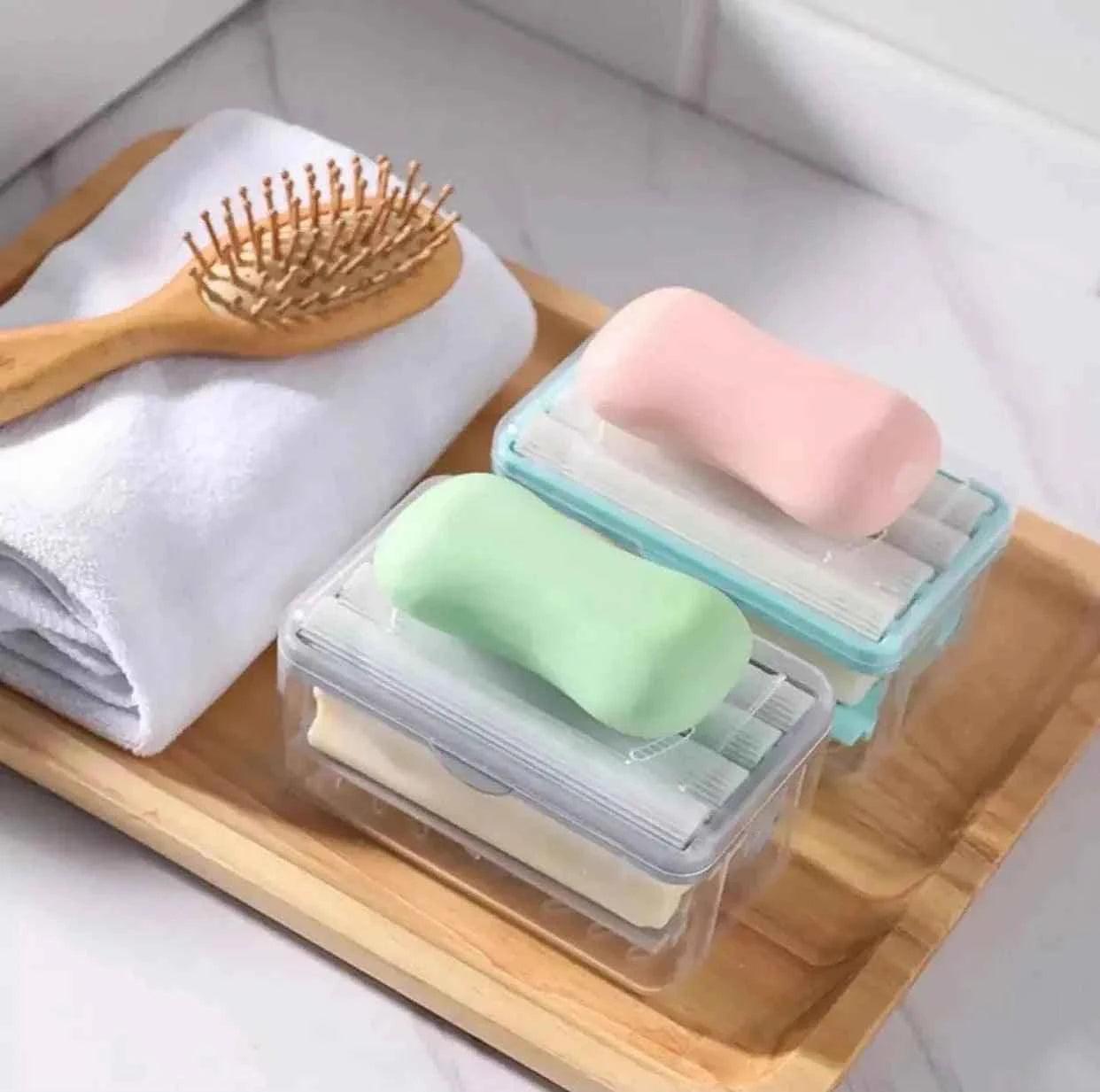 Hands-free soap dispenser with soap bars in clear containers on wooden tray with towel and hairbrush