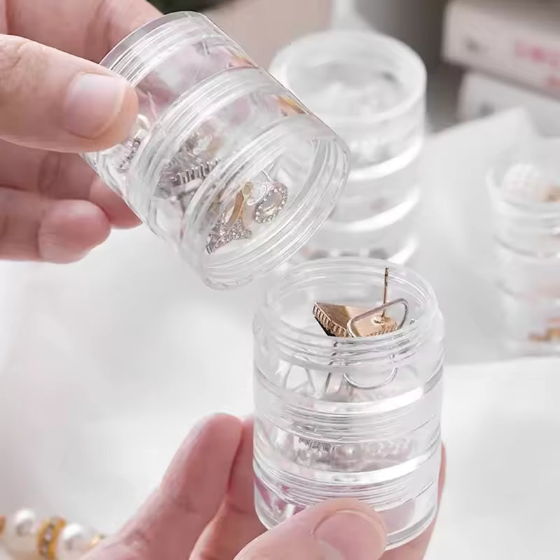 Clear 5 layer jewelry storage box by Clarify.pk holding various earrings in a compact design
