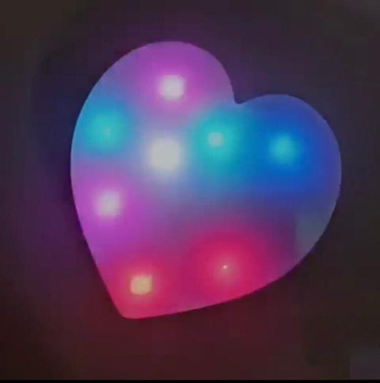 Colorful heart shaped LED lamp glowing with pink, blue, and purple lights on a dark background